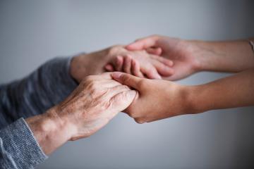 (imagem das mãos de um idoso segurando mãos de um jovem)