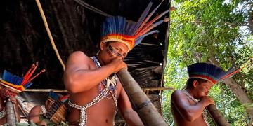 Indígena tocando instrumento típico de sua cultura